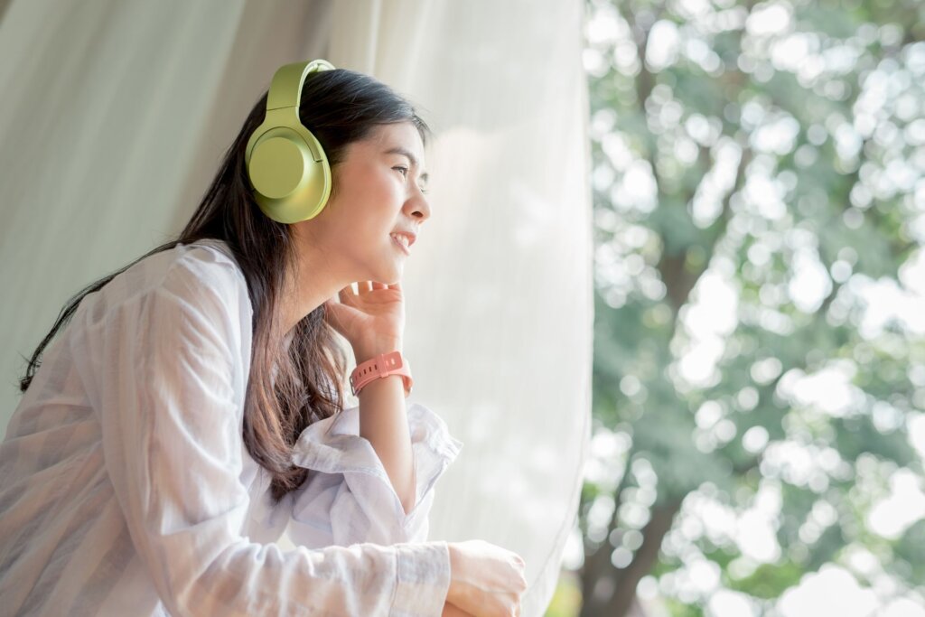 夏に外を眺めながら音楽を聴く女性